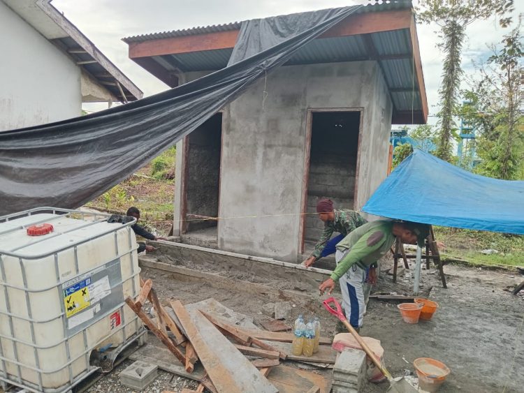 Personel Satgas TMMD bersama warga setempat melaksanakan pengecoran lantai teras MCK secara gotong royong. (Foto: NM)
