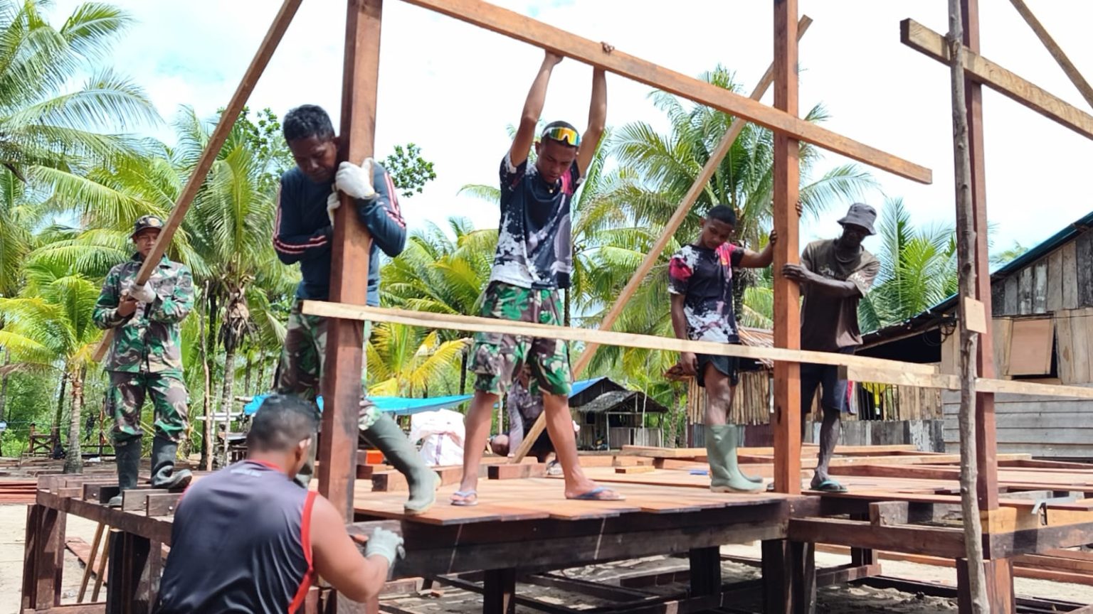 Personel Satgas TMMD bersama warga setempat tengah melaksanakan pemasangan rangka rumah. (Foto: Istimewa)